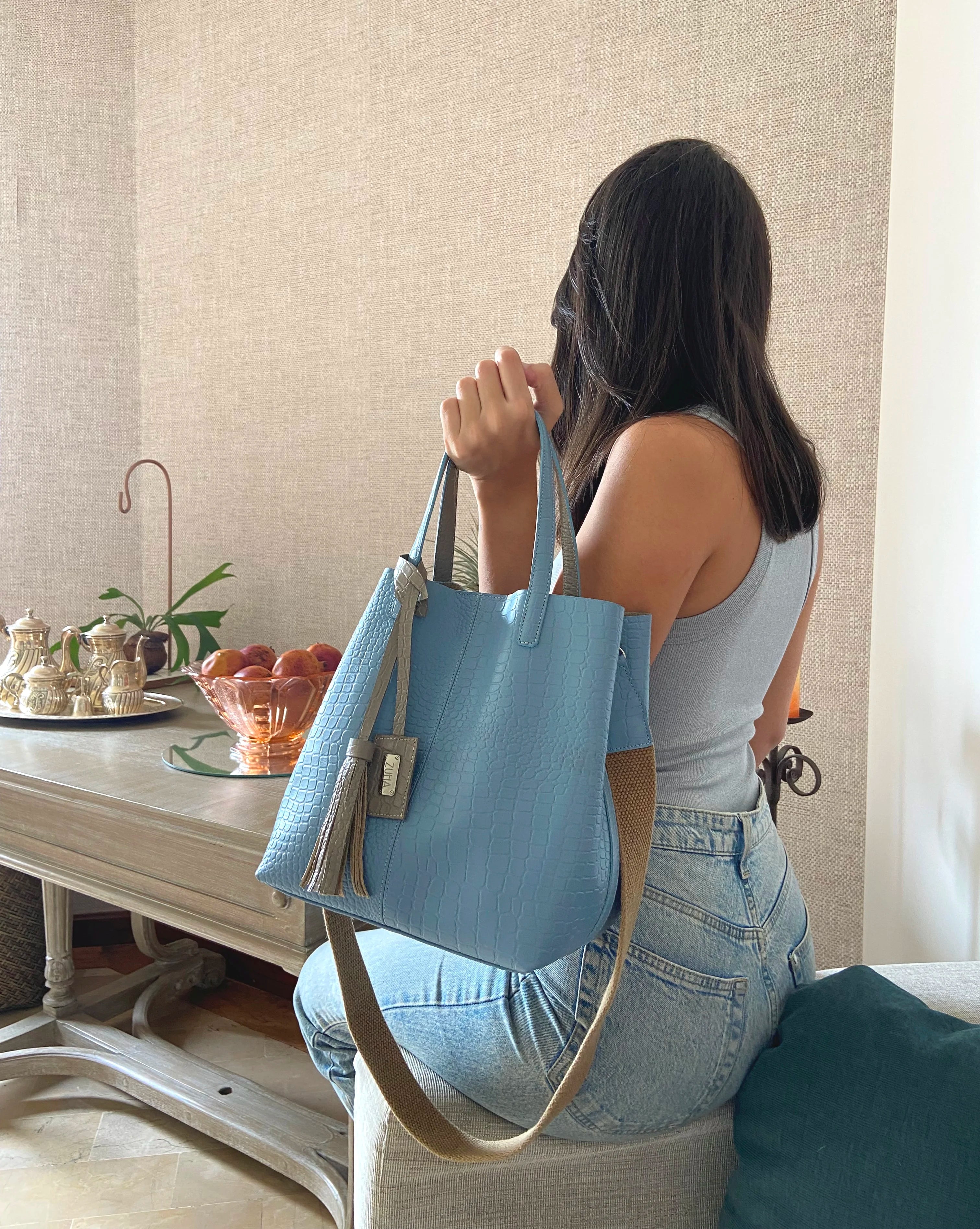 Mujer con bolso en cuero en la mano color azul celeste