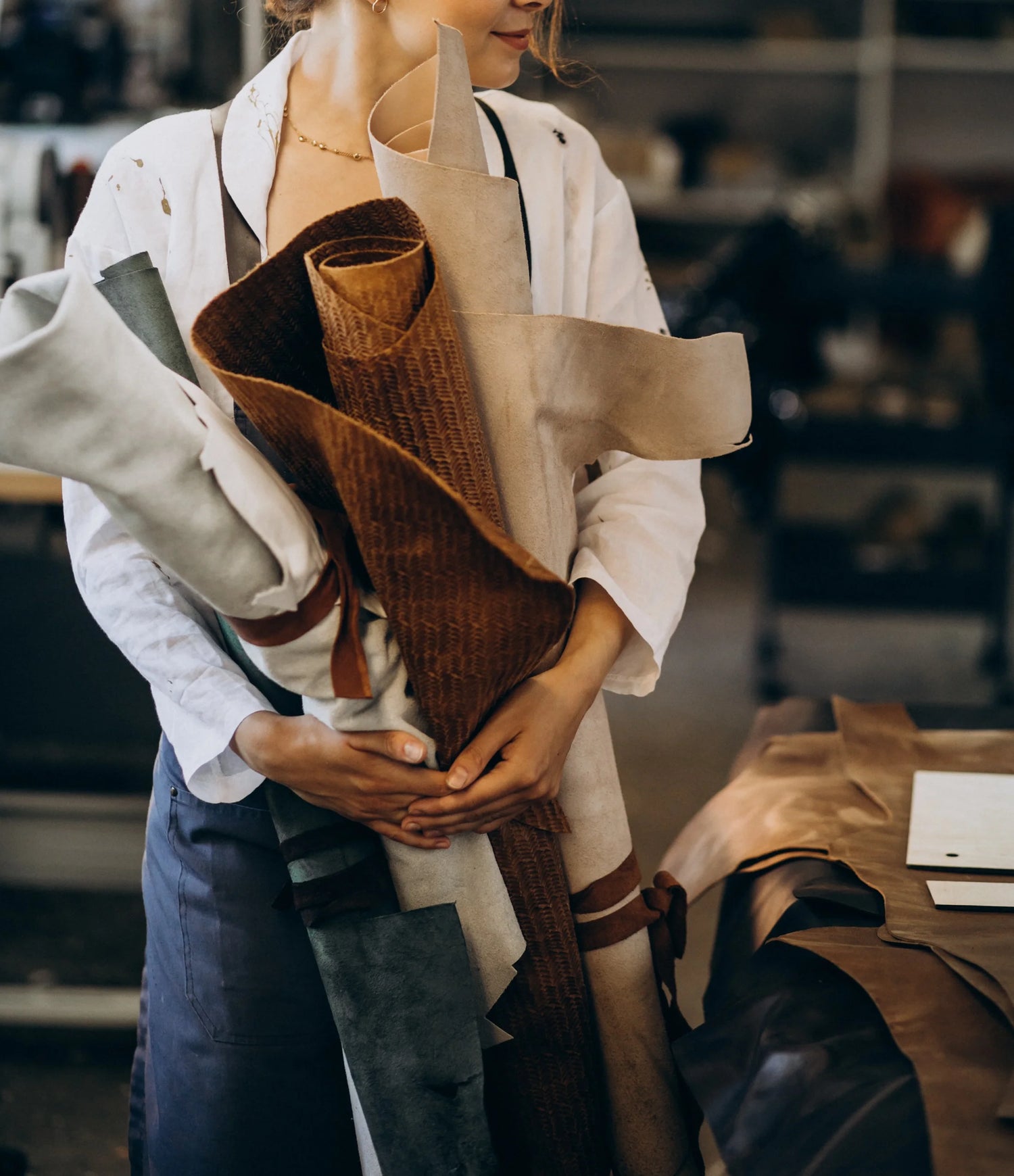 Mujer sosteniendo cueros en la fabrica de bolsos ZUHA